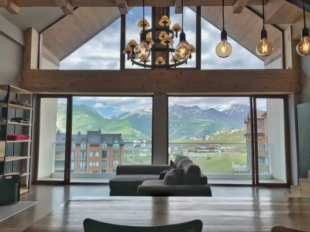 Le séjour de Maison Georgia, canapé face aux baies vitrées et aux montagnes de Gudauri